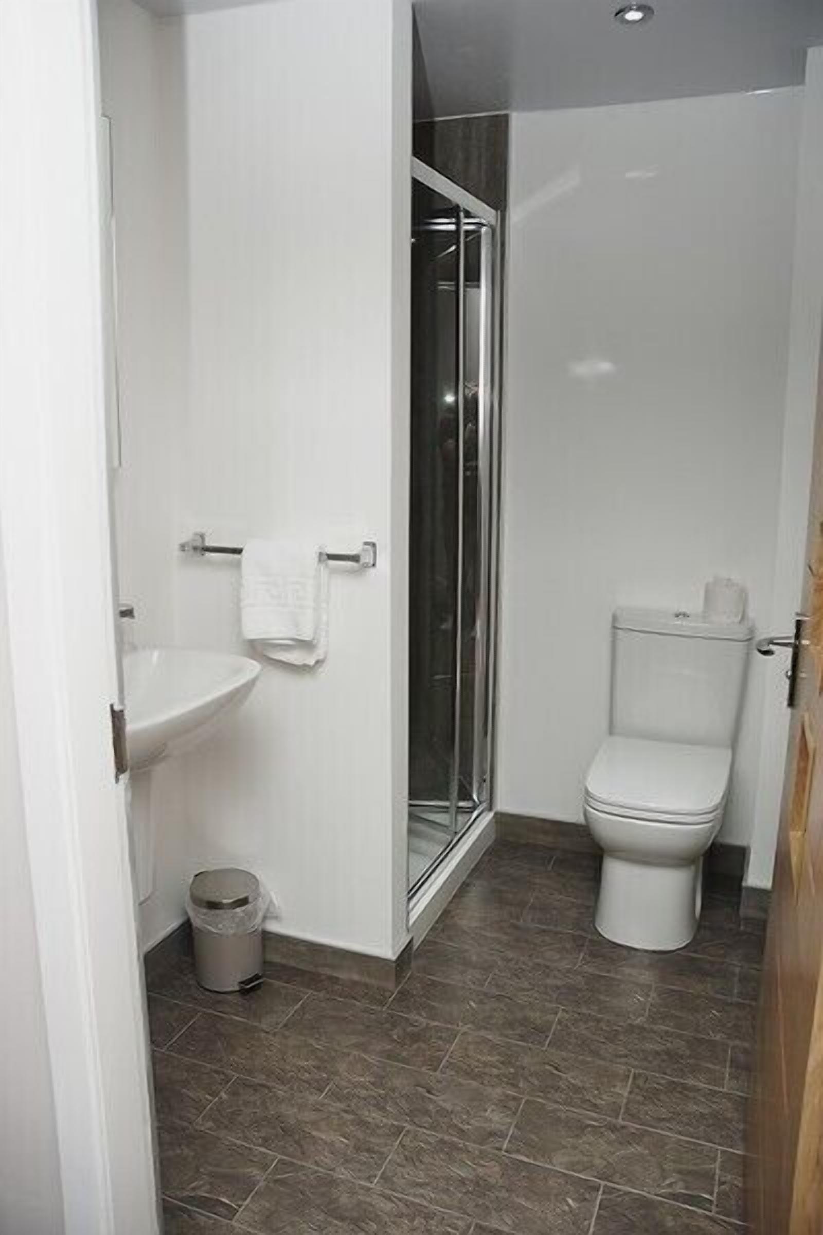 Un baño con lavamanos blanco, inodoro y cabina de ducha de vidrio.