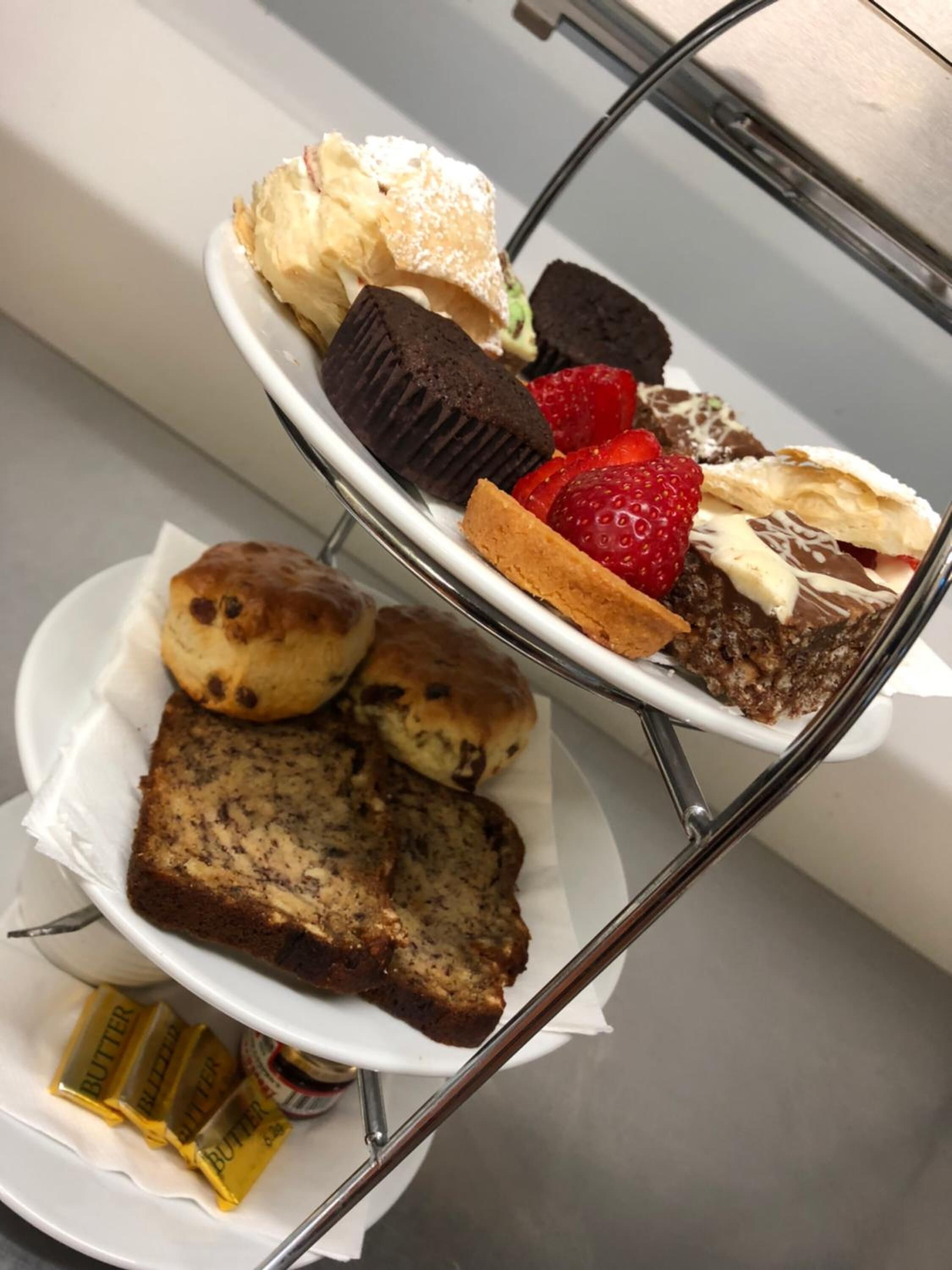 Una presentación de postres con diversos pasteles y tartas sobre un soporte de metal.