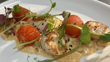 Un plato de mariscos con almejas a la plancha, tomates cherry y vegetales verdes.