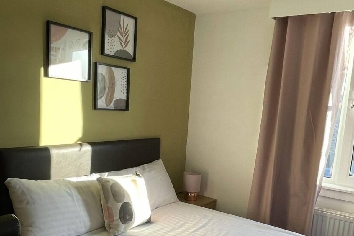 A hotel room with a bed, a nightstand, a lamp, and framed artwork on the wall.