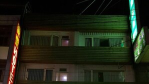 A hotel with a green signboard, multiple floors, and a visible entrance. - Happy Holiday Hotel (Taoyuan City)