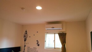 A room with a window, air conditioning unit, and wall decorations. - Happy Holiday Hotel (Taoyuan City)