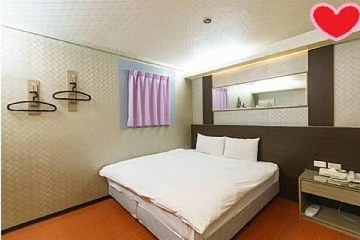Une chambre d’hôtel avec un lit, une table de chevet avec un téléphone et un miroir au-dessus du lit.
