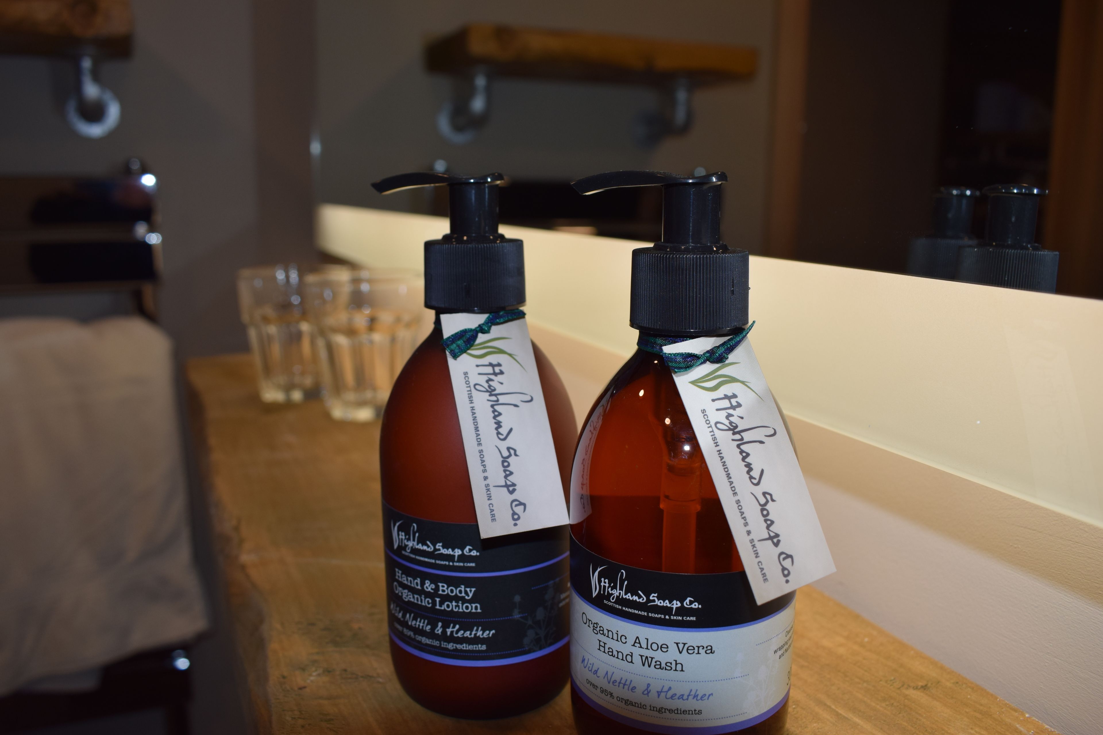 Dos botellas de jabón de manos orgánico sobre una encimera de madera.