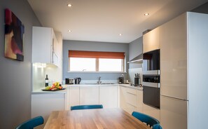 Eine moderne Küche mit weißen Schränken, einem Holztisch und blauen Stühlen.