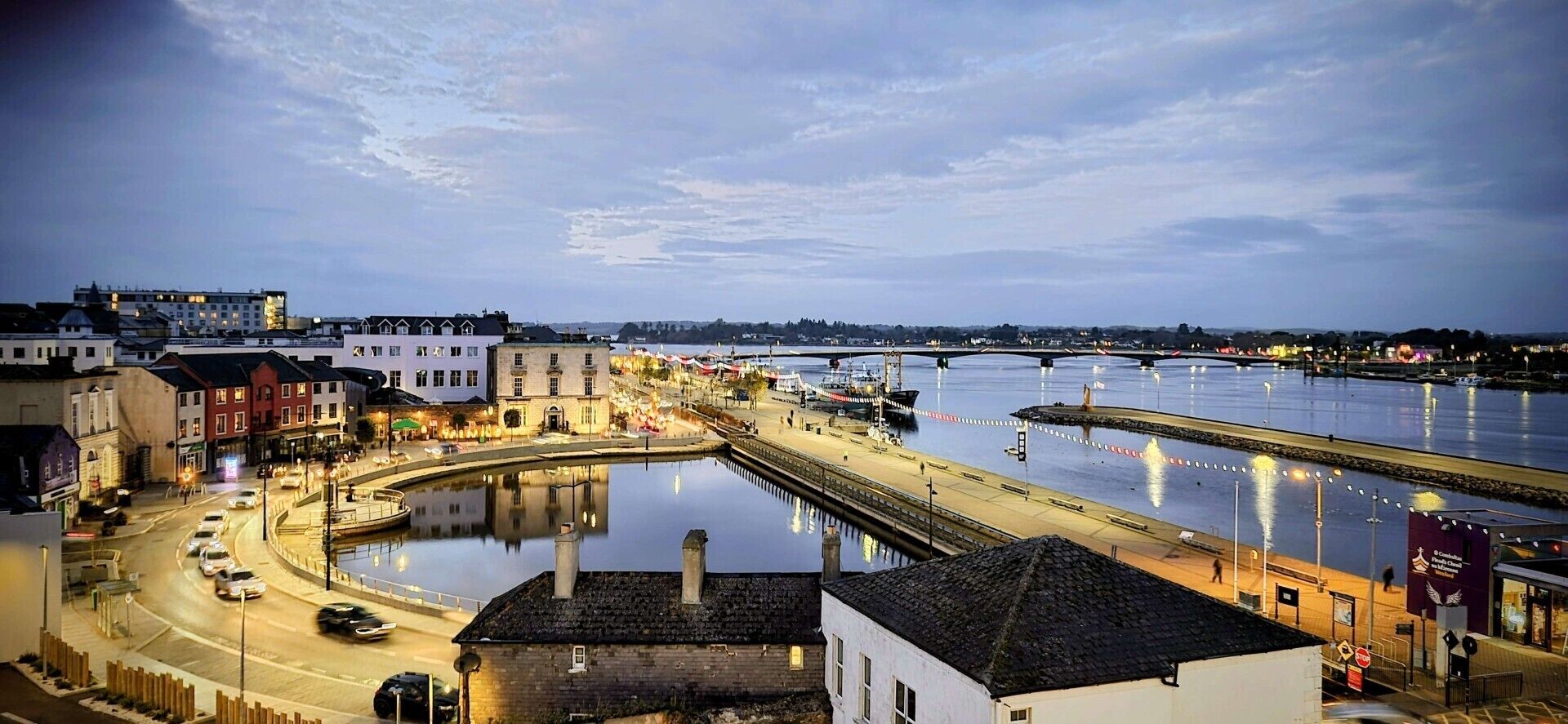 A waterfront cityscape with buildings, a bridge, and a calm river.