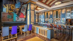 A bar area with wooden furniture, a counter with a cash register, and a variety of bottles on shelves. - Talbot Suites at Stonebridge (Wexford)