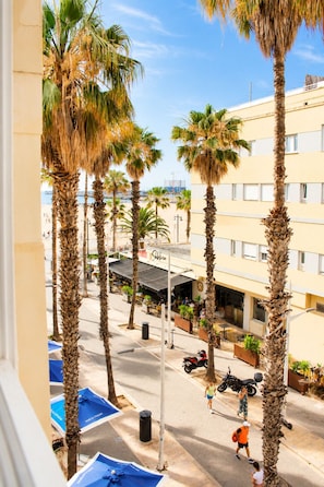 A street view with palm trees, a building with a sign 'Subito', and a clear sky. - Malvarrosa Beach Rooms (Valencia)