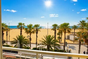 A beach view with palm trees, a clear sky, and the ocean. - Malvarrosa Beach Rooms (Valencia)