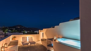 A rooftop terrace with a pool, seating area, and a view of the city at night. - Villa Aegeon Grande (Santorini)