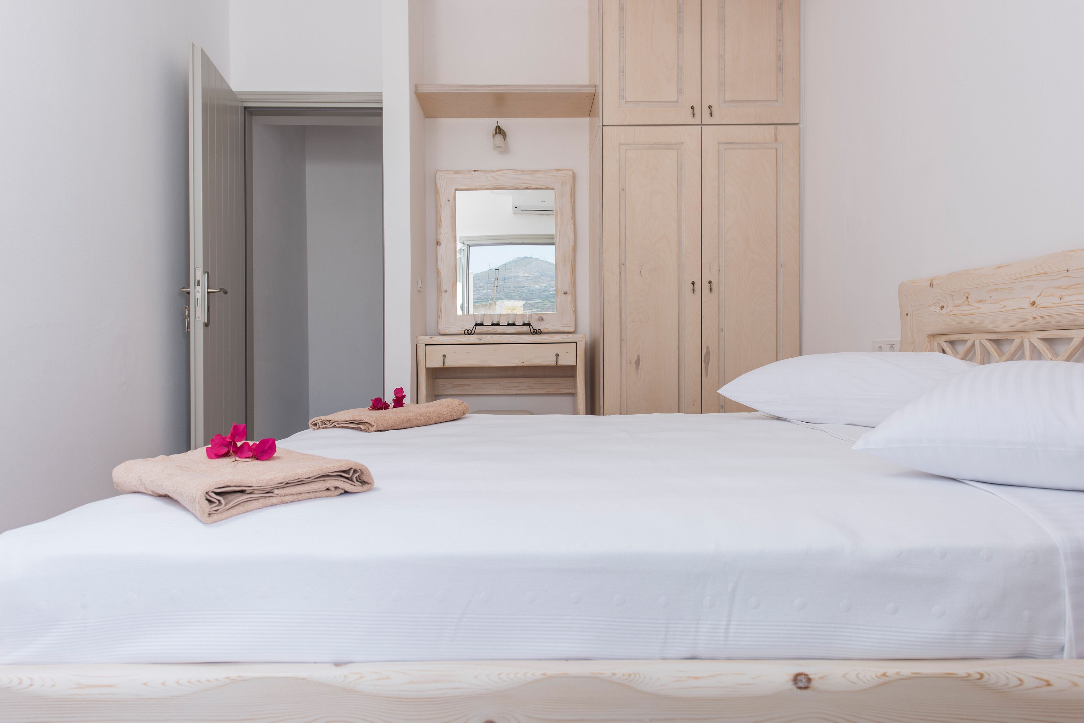 Un dormitorio con cama, cabecera de madera, armario de madera y espejo sobre la cómoda.