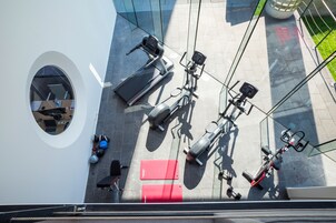 Vue d’ensemble d’une salle de sport équipée de divers appareils, notamment des tapis de course, des vélos d’appartement et des poids.