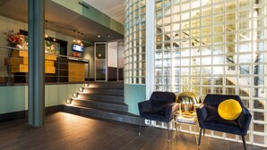 A modern lobby with a staircase, a reception desk, and seating area with a yellow pillow. - Hotel2Stay (Amsterdam)