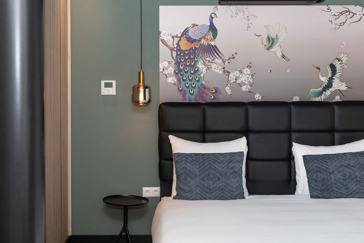 A bedroom with a large bed, a modern headboard, and a wall mural of birds and flowers.