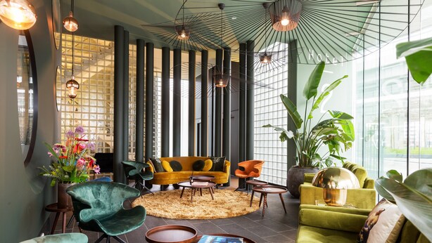 A modern hotel lobby with a yellow sofa, green armchairs, and a large potted plant. - Hotel2Stay (Amsterdam)