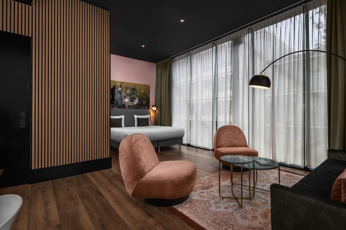 A modern living room with a sofa, armchairs, a coffee table, and a painting on the wall.