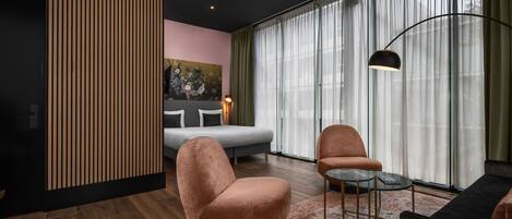 Una sala de estar moderna con un sofá, sillones, una mesa de centro y un cuadro en la pared.