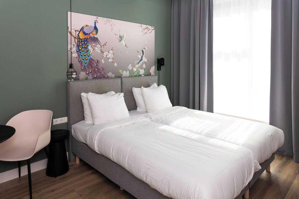 A modern hotel room with a large bed, a desk, and a decorative wall piece.