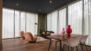 A modern living room with a wooden floor, a green sofa, a pink armchair, a dining table with chairs, and a floor lamp. - Hotel2Stay (Amsterdam)