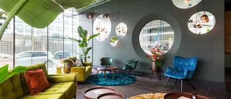 A modern interior with a green sofa, a blue chair, and a round table with a book.