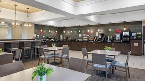 Un hall d’hôtel moderne avec un bar central, des espaces aménagés pour s’asseoir et une poubelle bien visible.
