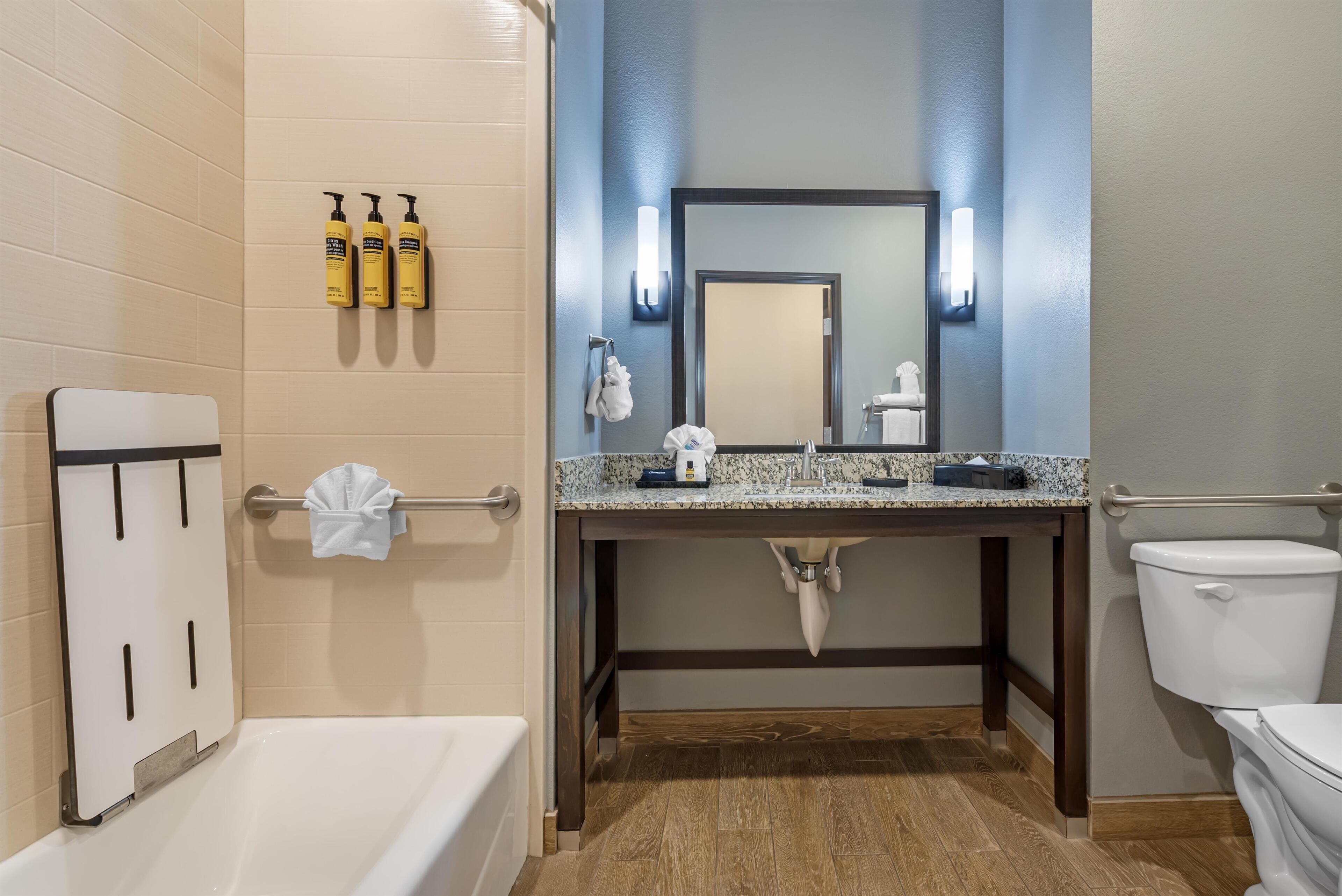 A bathroom with a bathtub, a sink with a mirror, and toiletries on the wall.