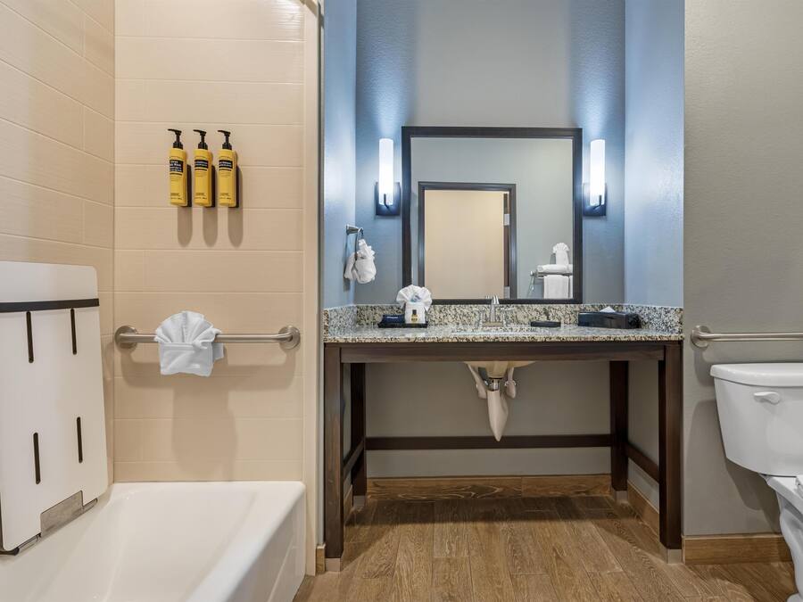 A bathroom with a bathtub, a sink with a mirror, and toiletries on the wall.