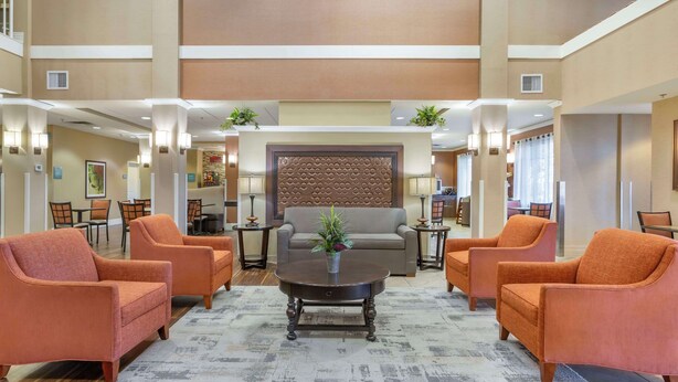 Een ruime lobby met een centraal zithoek, inclusief een bank en fauteuils, een decoratieve wand en sfeervolle verlichting.