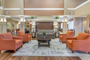 A spacious lobby with a central seating area featuring a sofa and armchairs, a decorative wall, and ambient lighting. - Best Western Plus Chandler Hotel & Suites (Chandler)