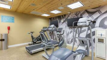 A fitness center with treadmills, elliptical machines, and a wall-mounted TV.