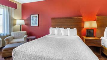 A hotel room with a large bed, a chair, a nightstand, and a lamp.