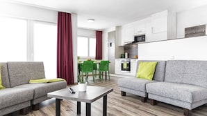 Una sala de estar moderna con un sofá gris, una mesa de centro y un comedor con sillas verdes.