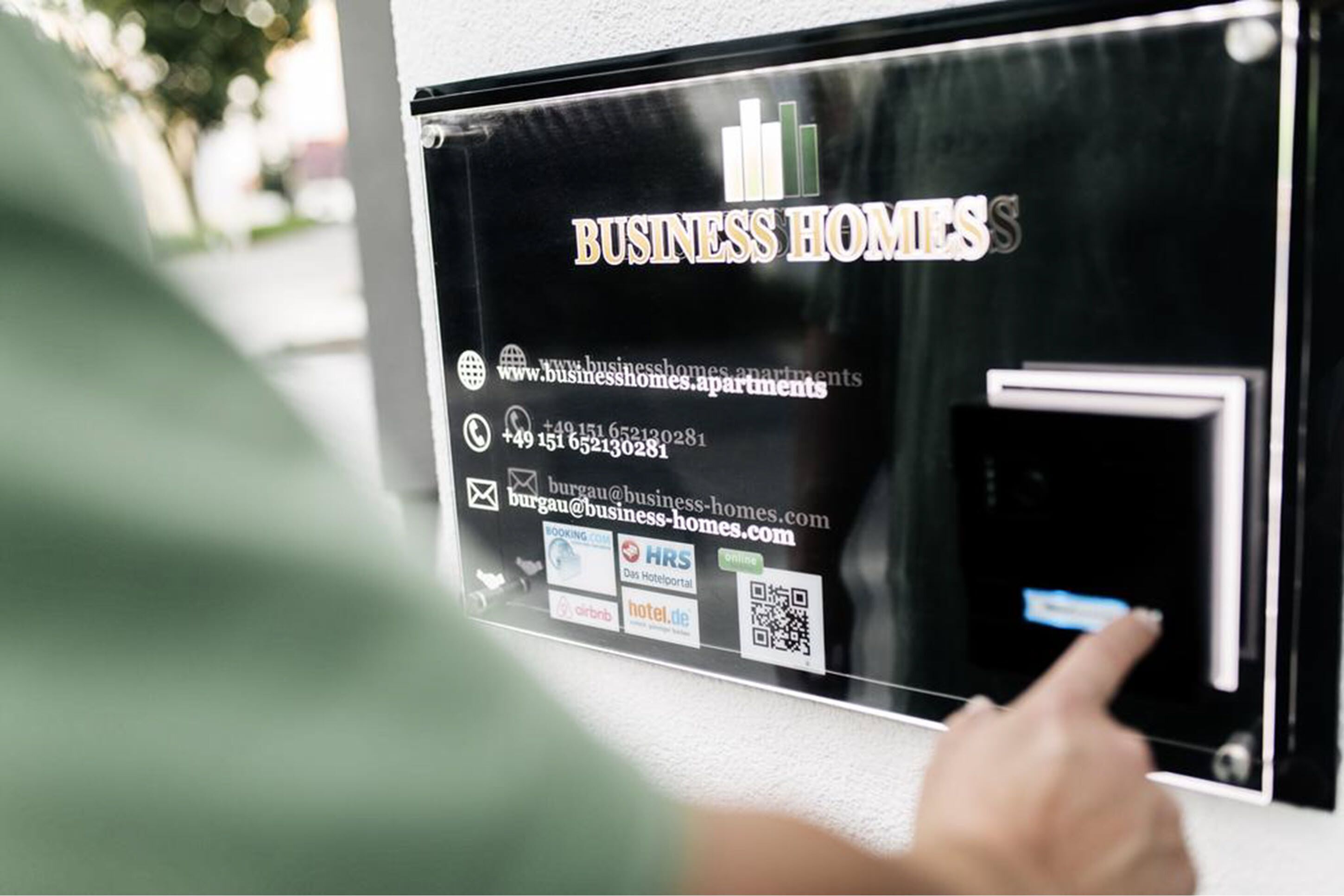 A digital display for BUSINESS HOMES with contact information and QR codes for booking and hotel portals.