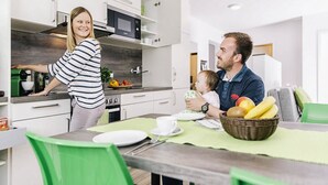 Una cocina moderna con armarios blancos, un microondas y un comedor con mantel verde.
