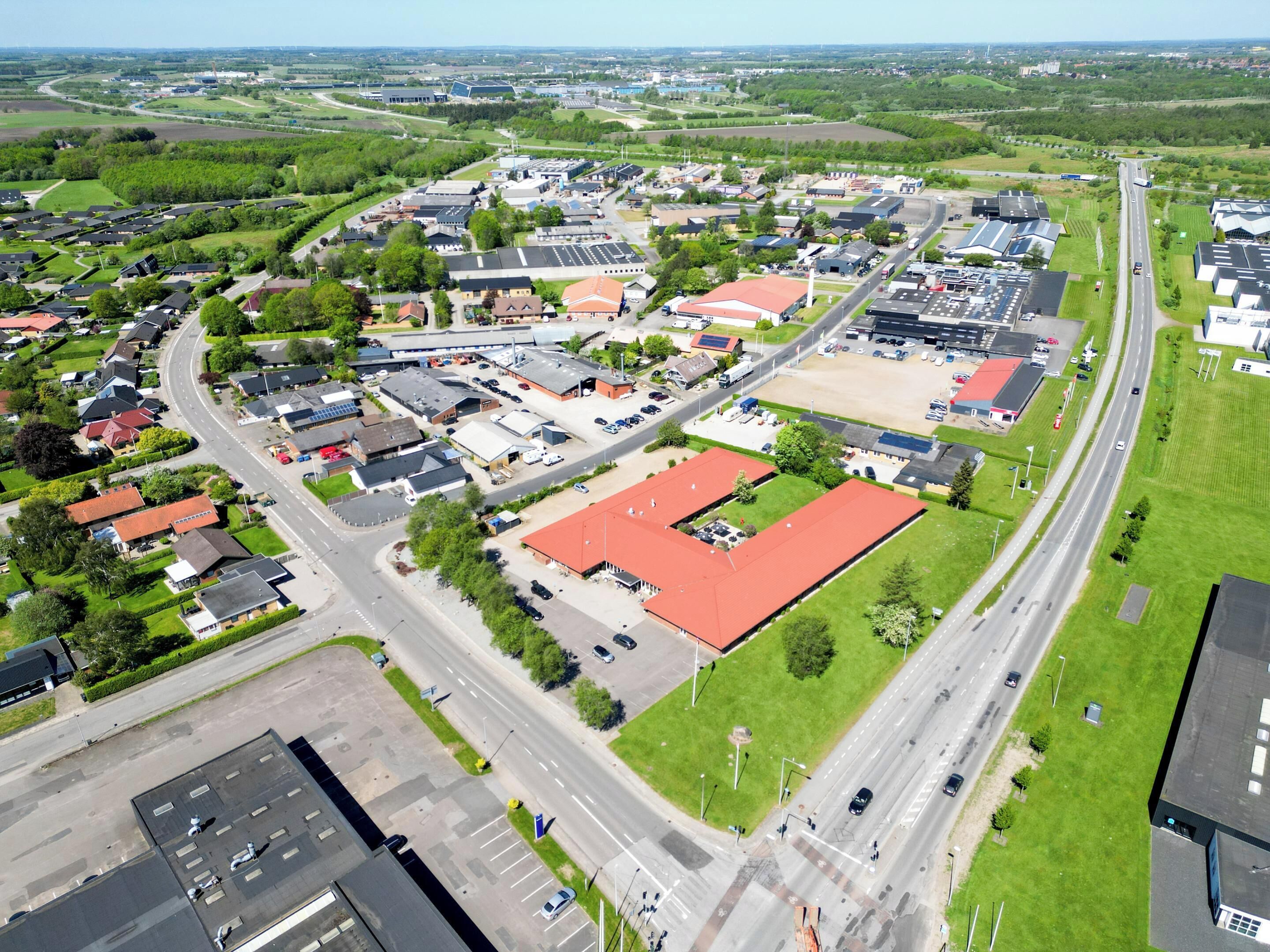 An aerial view of a residential area with houses, roads, and a large industrial building.