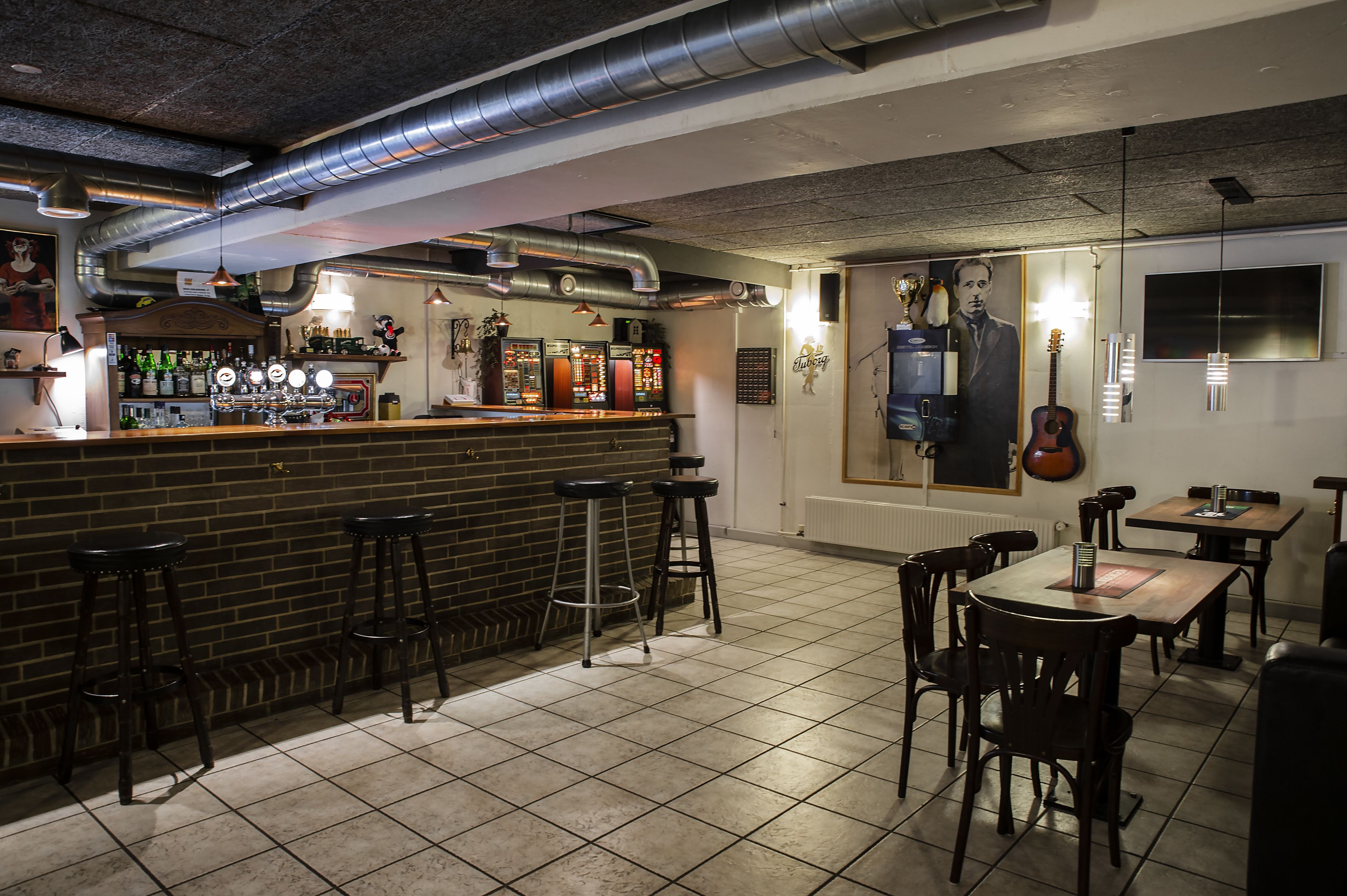 A bar area with stools, a counter with bottles, and a mural on the wall.