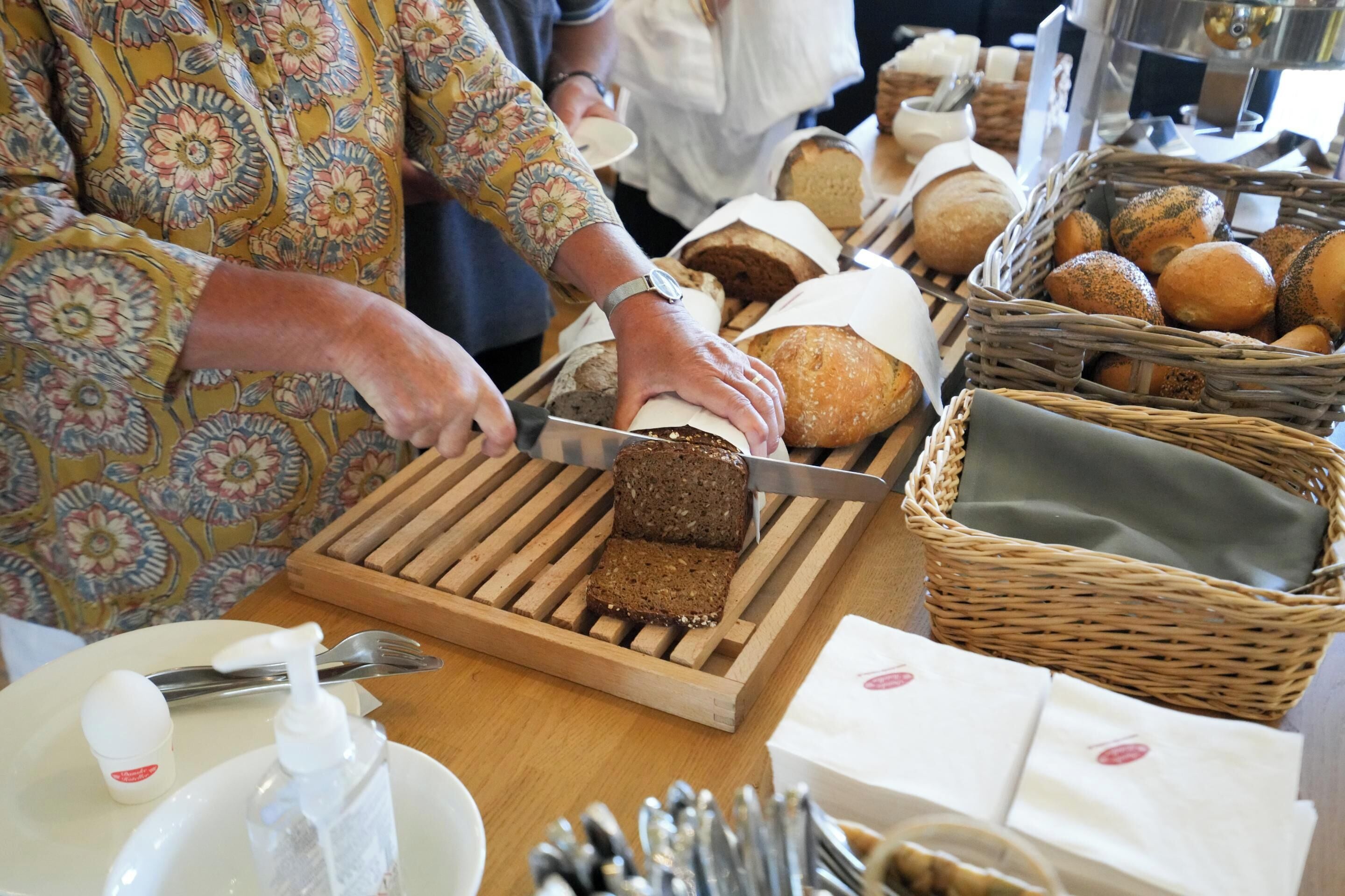 Eine Person schneidet ein Brot auf einem Holzbrett.