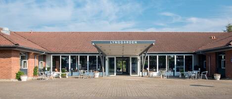 A building with a tiled roof and a covered entrance area with outdoor seating.