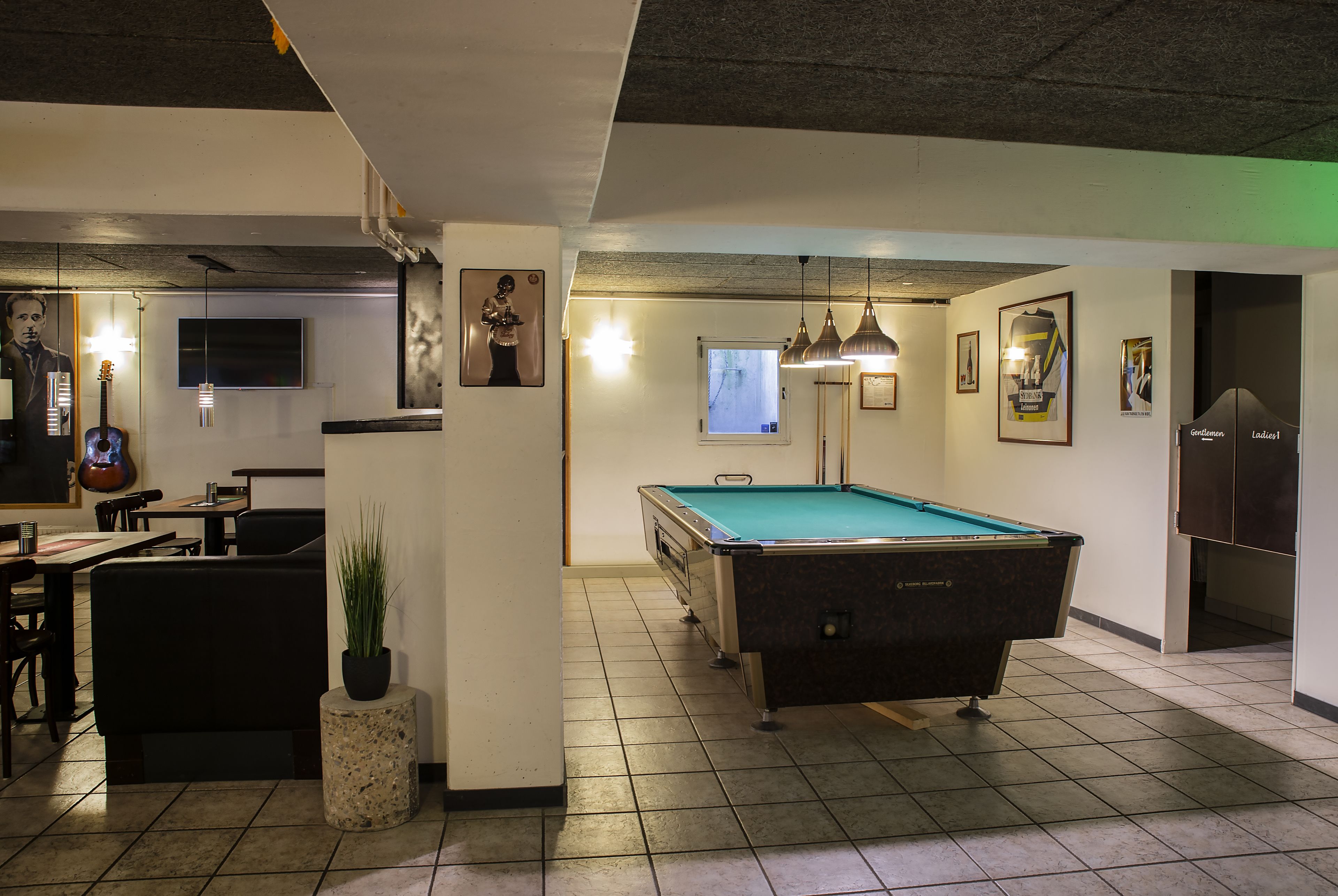 A billiards room with a pool table, seating area, and a television.