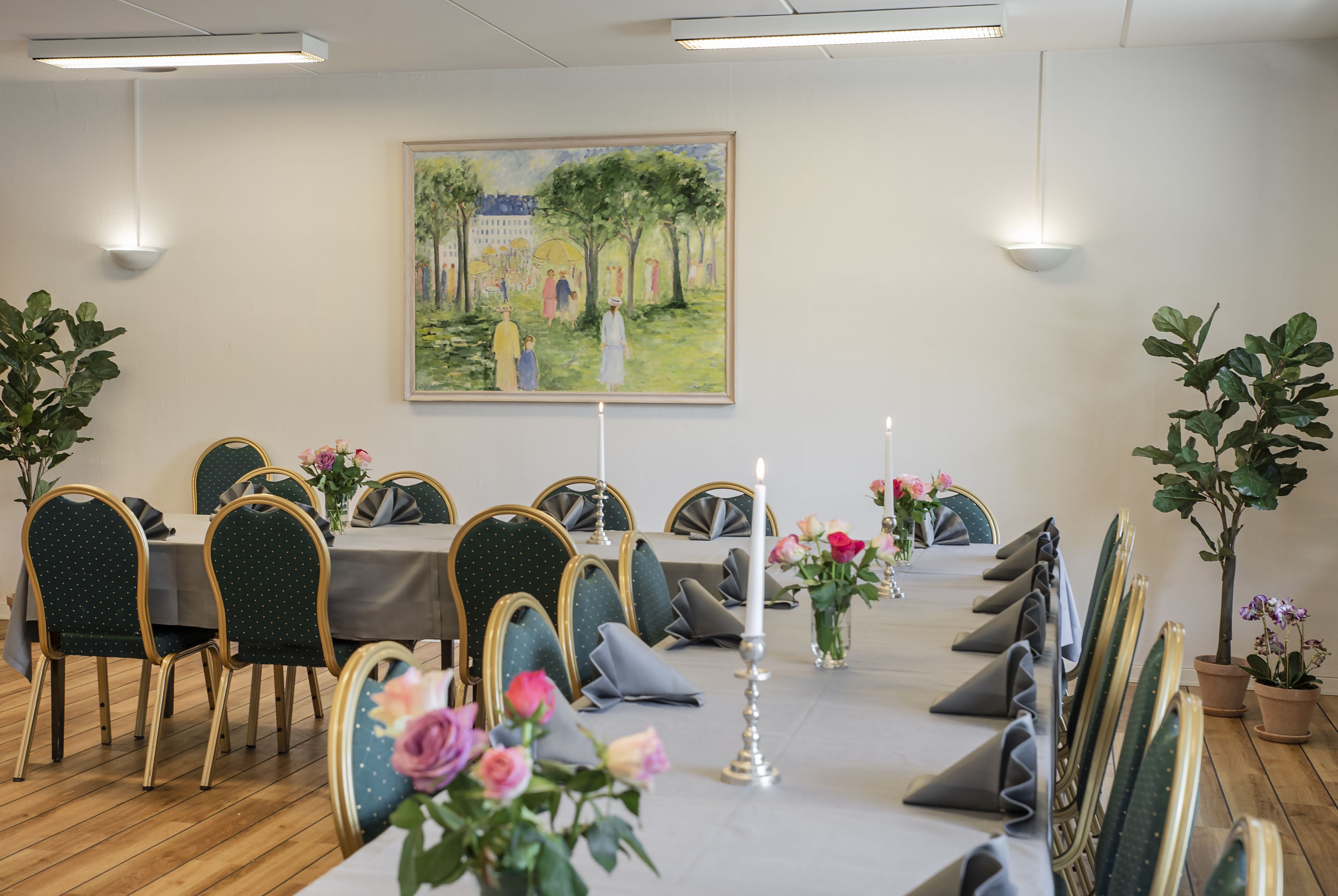 A dining area with a long table, chairs, and a painting on the wall.