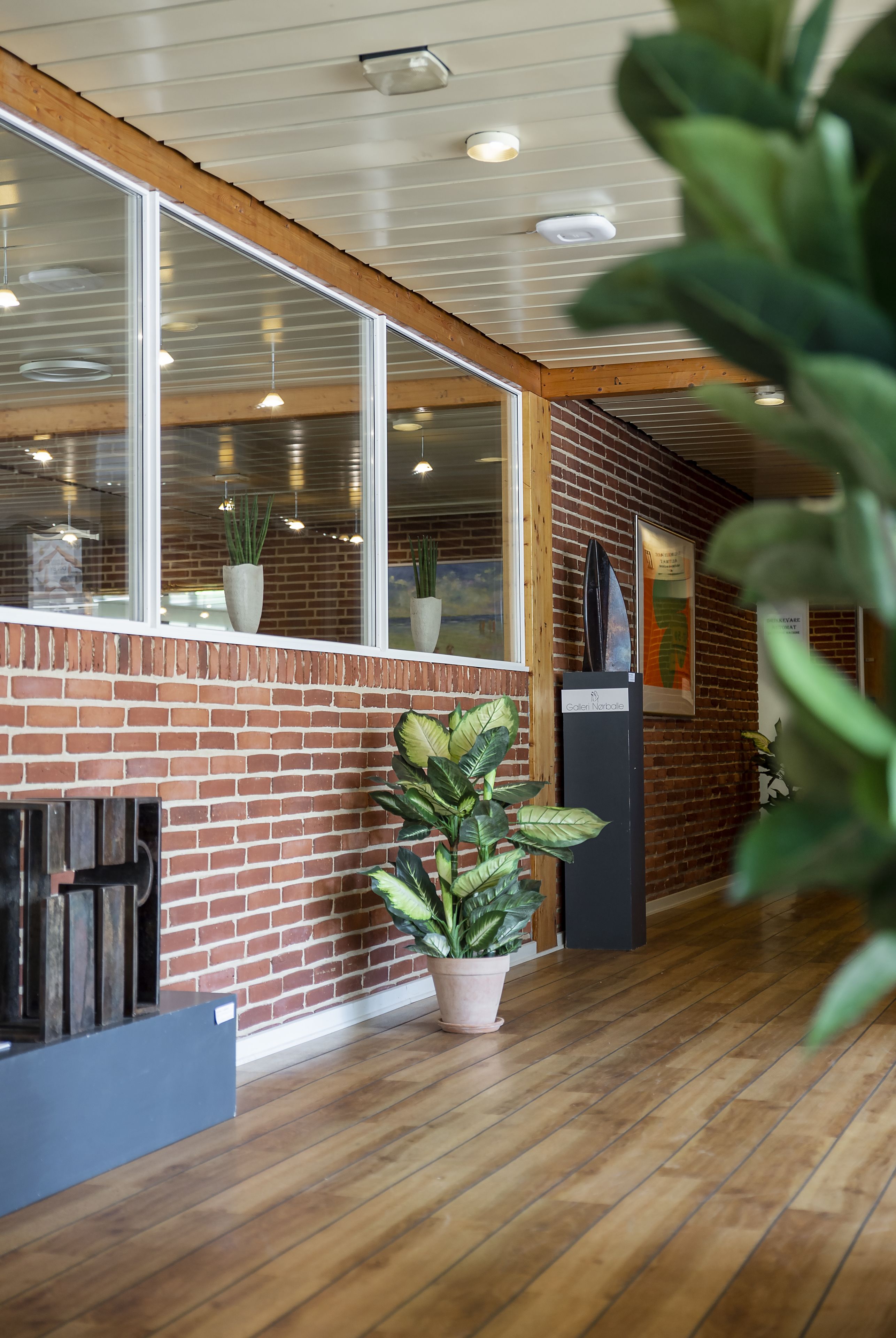 A modern interior with a brick wall, wooden flooring, and large windows.