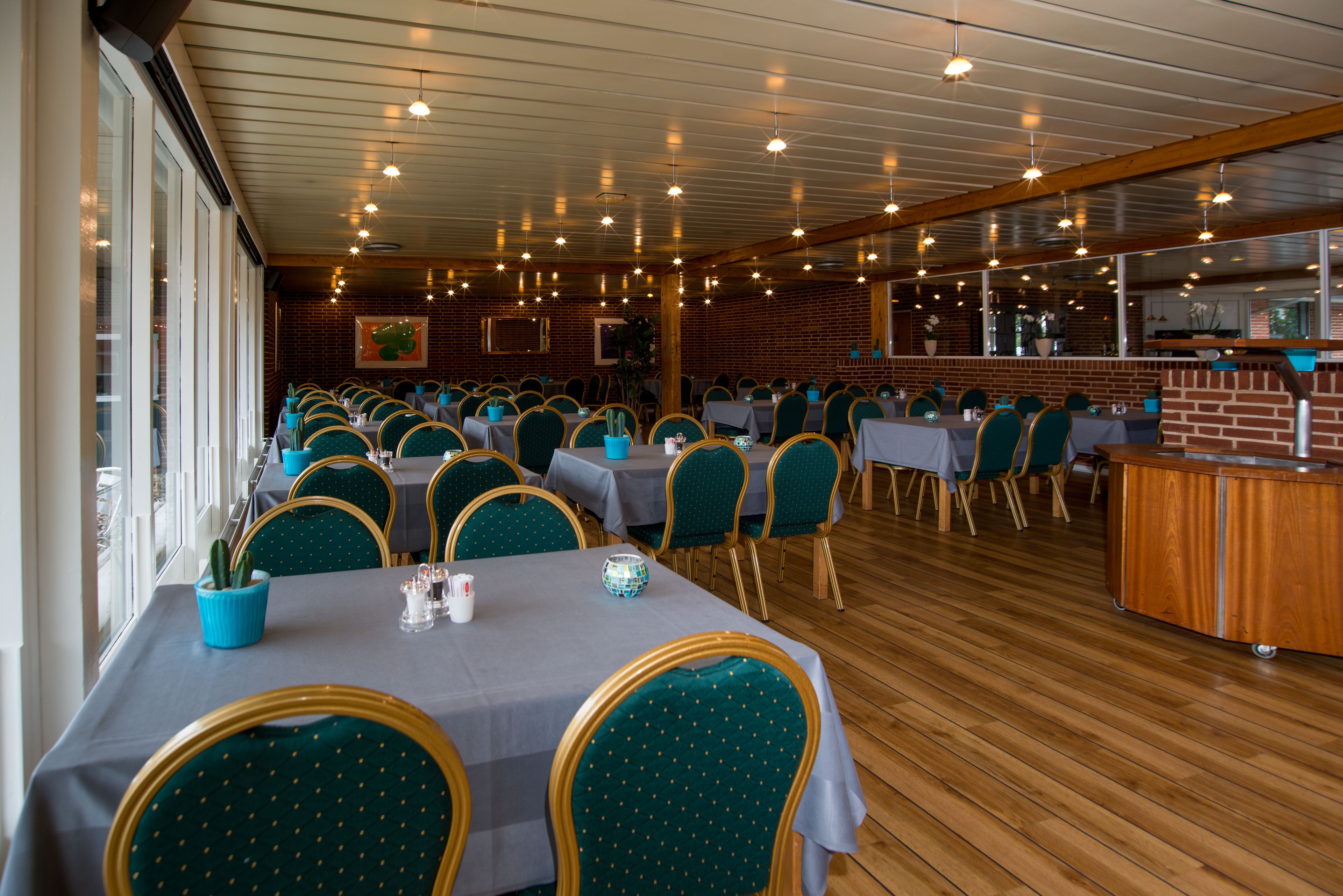 A restaurant with multiple tables and chairs, a brick wall, and a wooden ceiling.