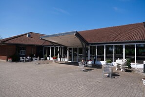 A building with a covered patio area, outdoor seating, and a sign reading "Pavement Garden."