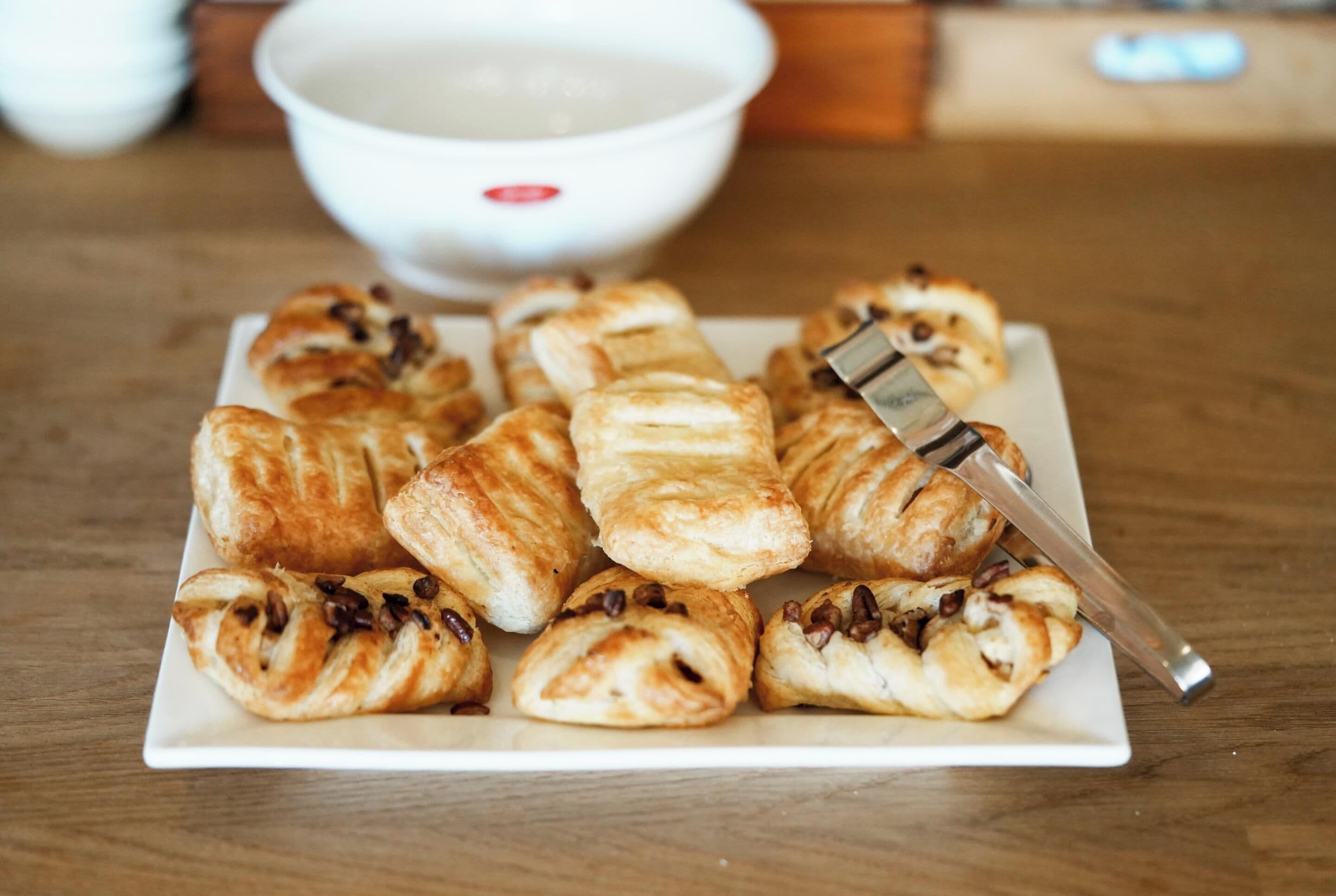 A plate of pastries with a knife on a wooden table.