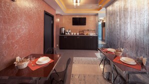 A modern hotel dining area with marble walls, a central kitchen, and a flat-screen TV. - Hotel Almira (Samara)