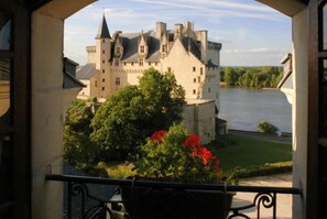 Un edificio de estilo castillo con un río al fondo, visto desde un balcón con barandilla.