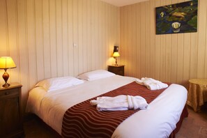 Una habitación de hotel con una cama, dos lámparas de noche, una mesita y un cuadro en la pared.