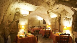 En restaurang som liknar en grotta, med bord och stolar, där varje bord har en duk och en lampa.