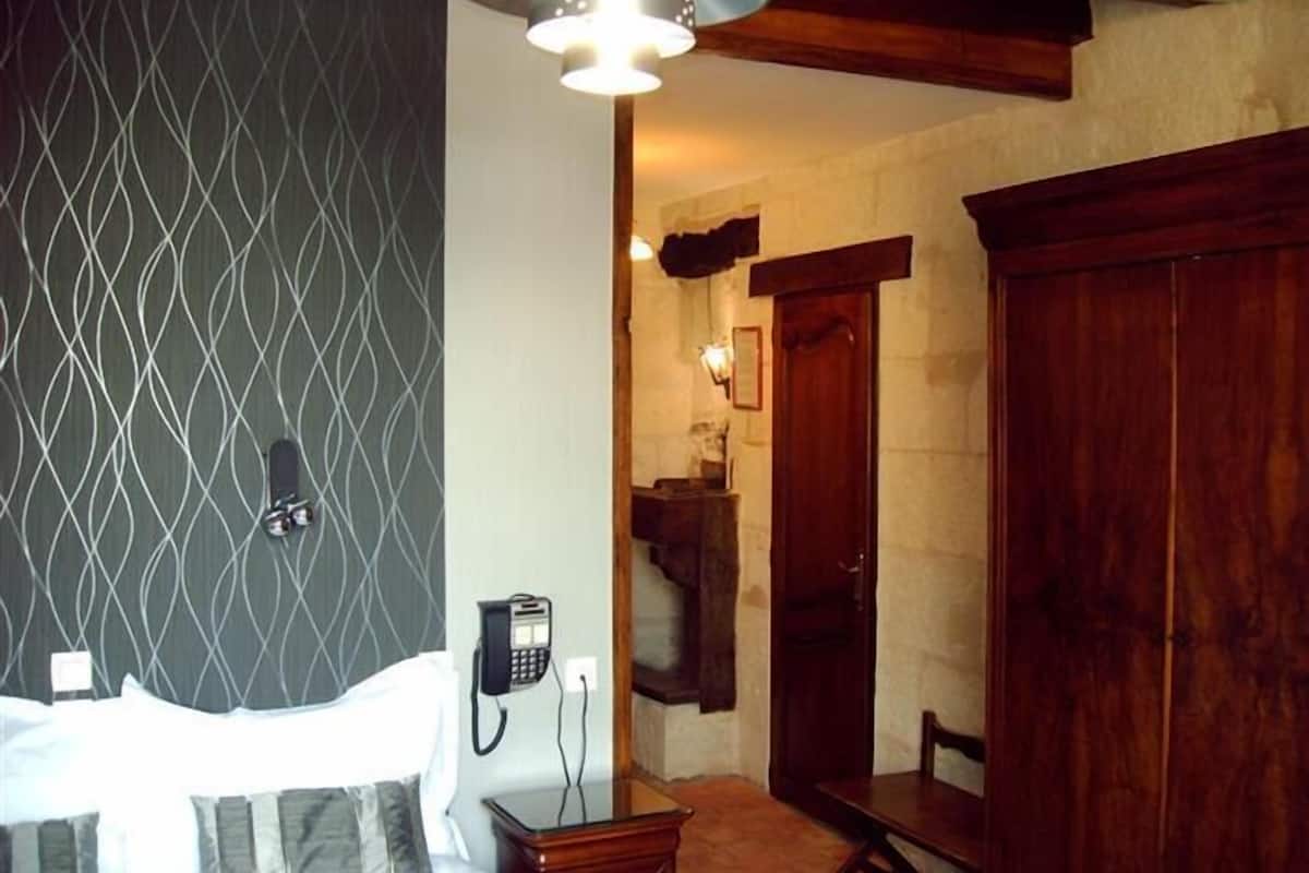 Une chambre d’hôtel avec un lit, un téléphone, une armoire en bois et un miroir.