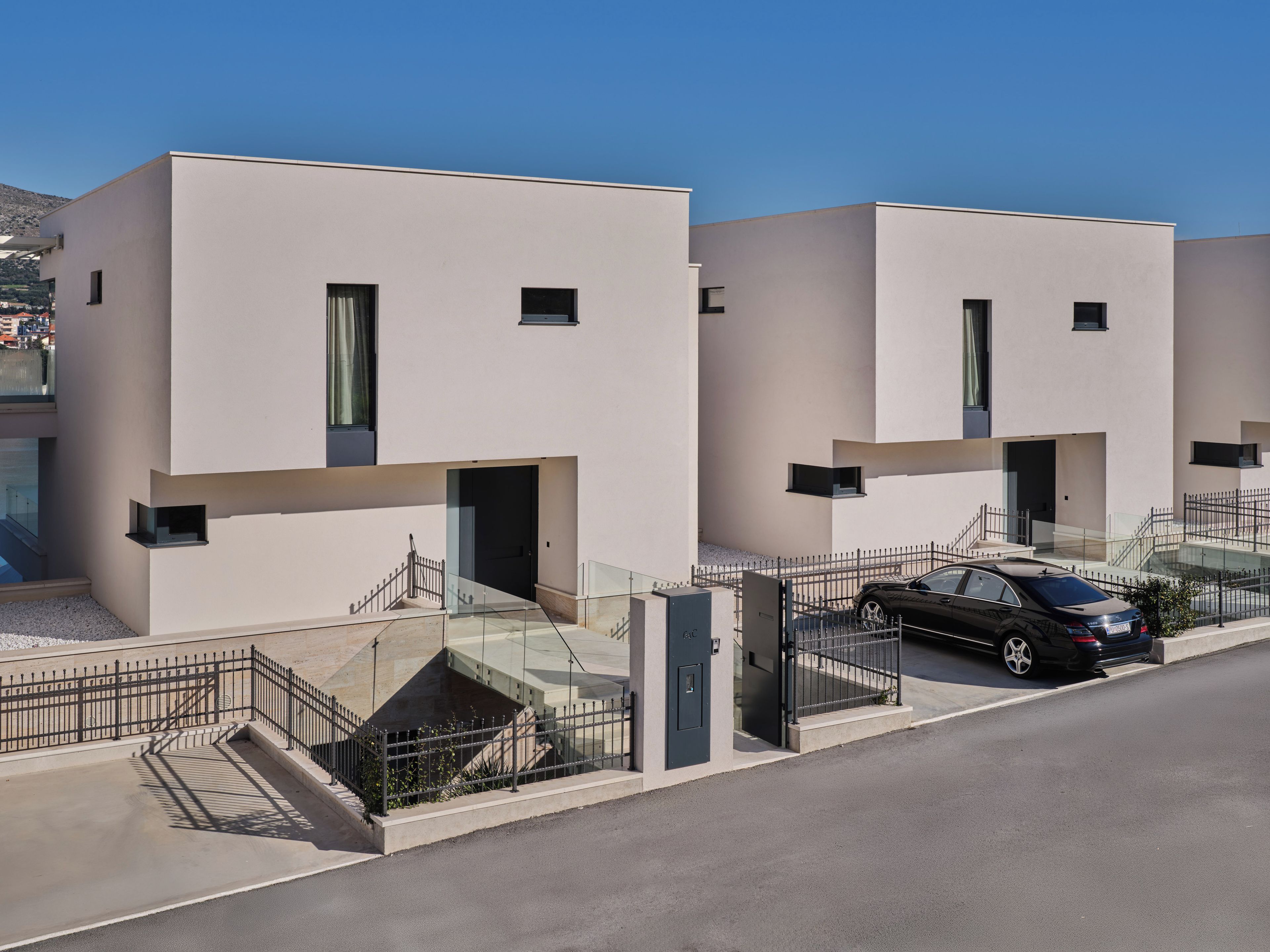 A modern residential building with a car parked in front.